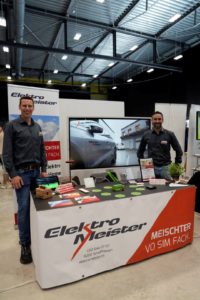 Zwei Mitarbeitende von Elektro Meister am Messestand mit Bildschirm und Broschüren